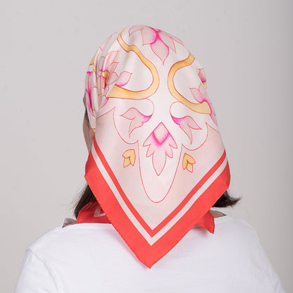 Person wearing a colorful headscarf with pink and red patterns on a plain background