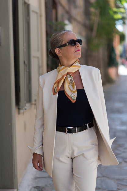 Woman in a stylish outfit with a cream silk scarf called Mesogeia Blooms worn in a knot around her neck is walking