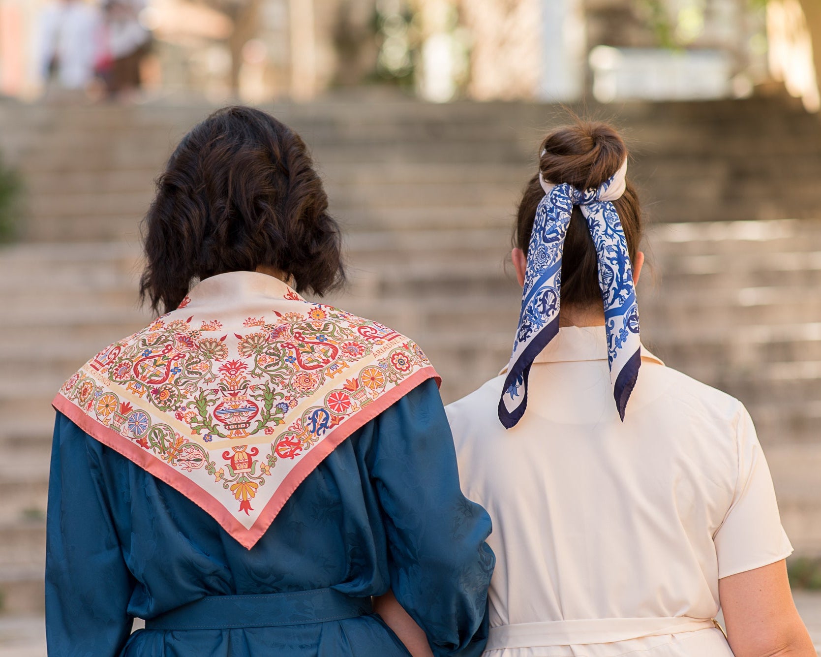 Blue and pink mermaid scarves made from Greek silk, are shown from the back as the models are walking up stairs
