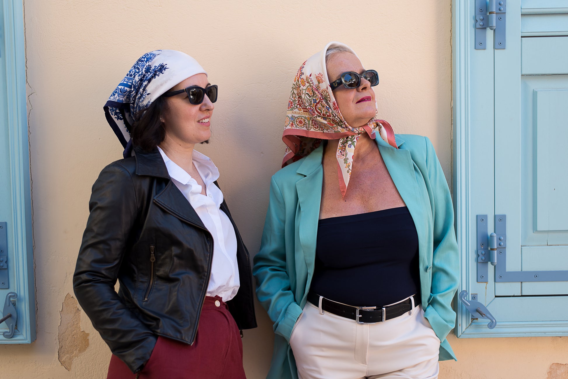 Two women wearing the Cretan Mermaid scarves in pink and blue as headscarves in dynamic poses