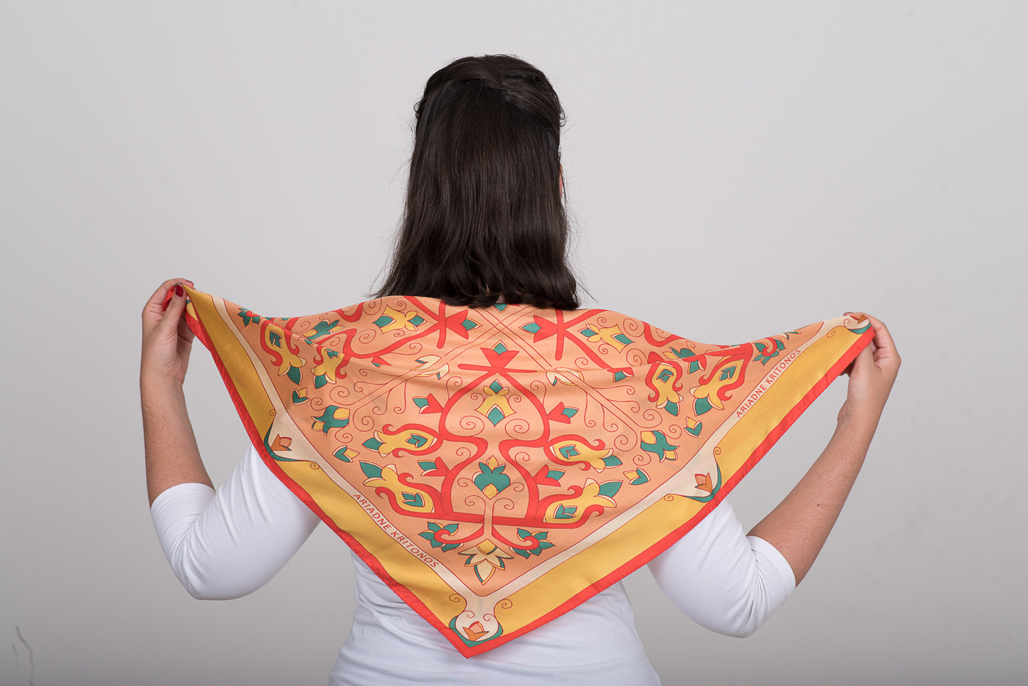 Floral orange, pink and red silk scarf tied at the back in simple styling pose to showcase the design