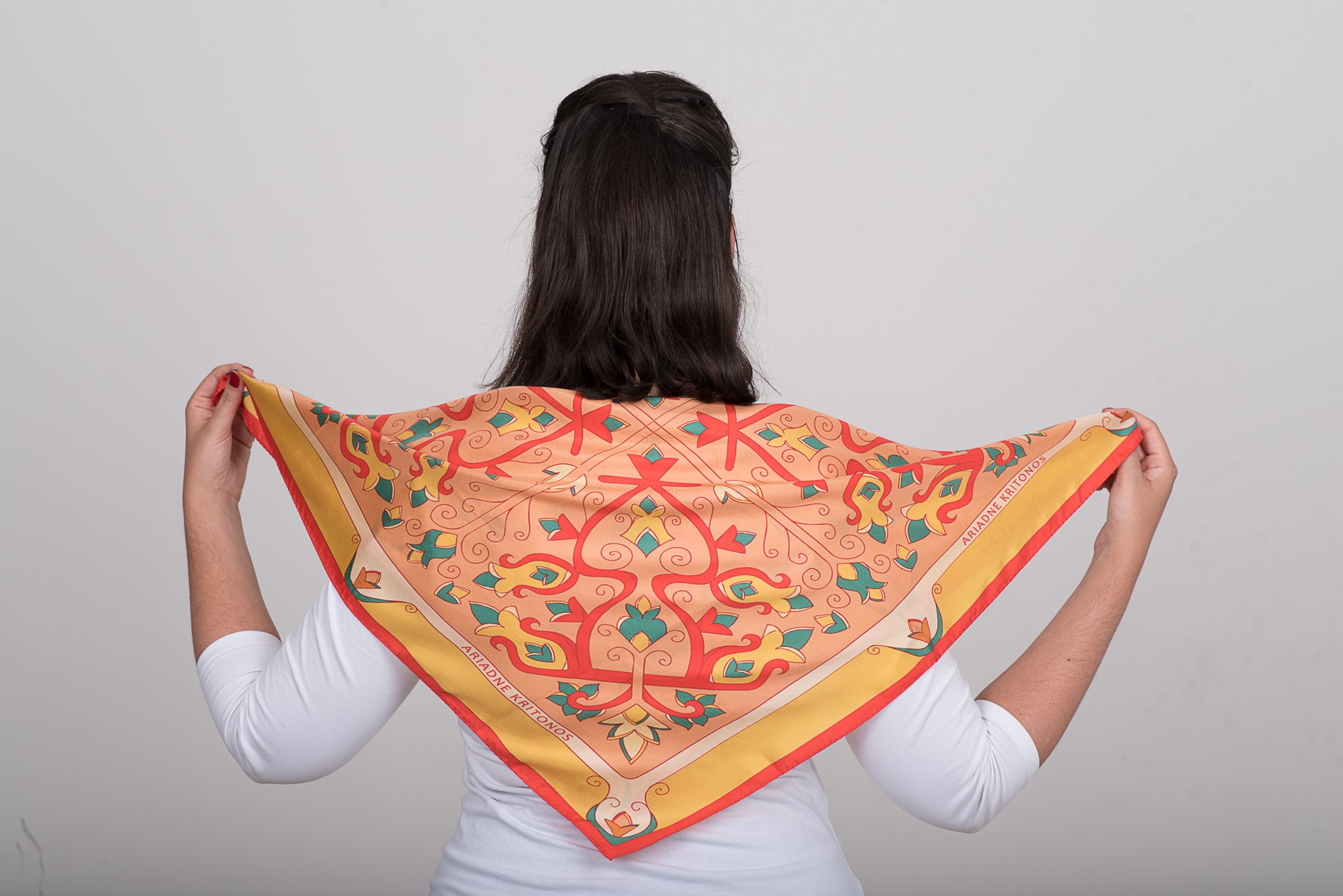 Floral orange, pink and red silk scarf tied at the back in simple styling pose to showcase the design