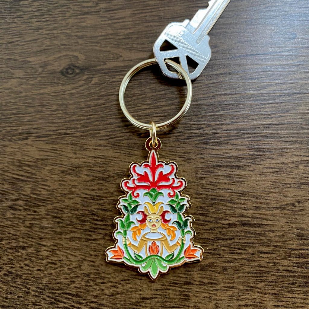 Decorative keychain with mermaid and floral design on a wooden surface