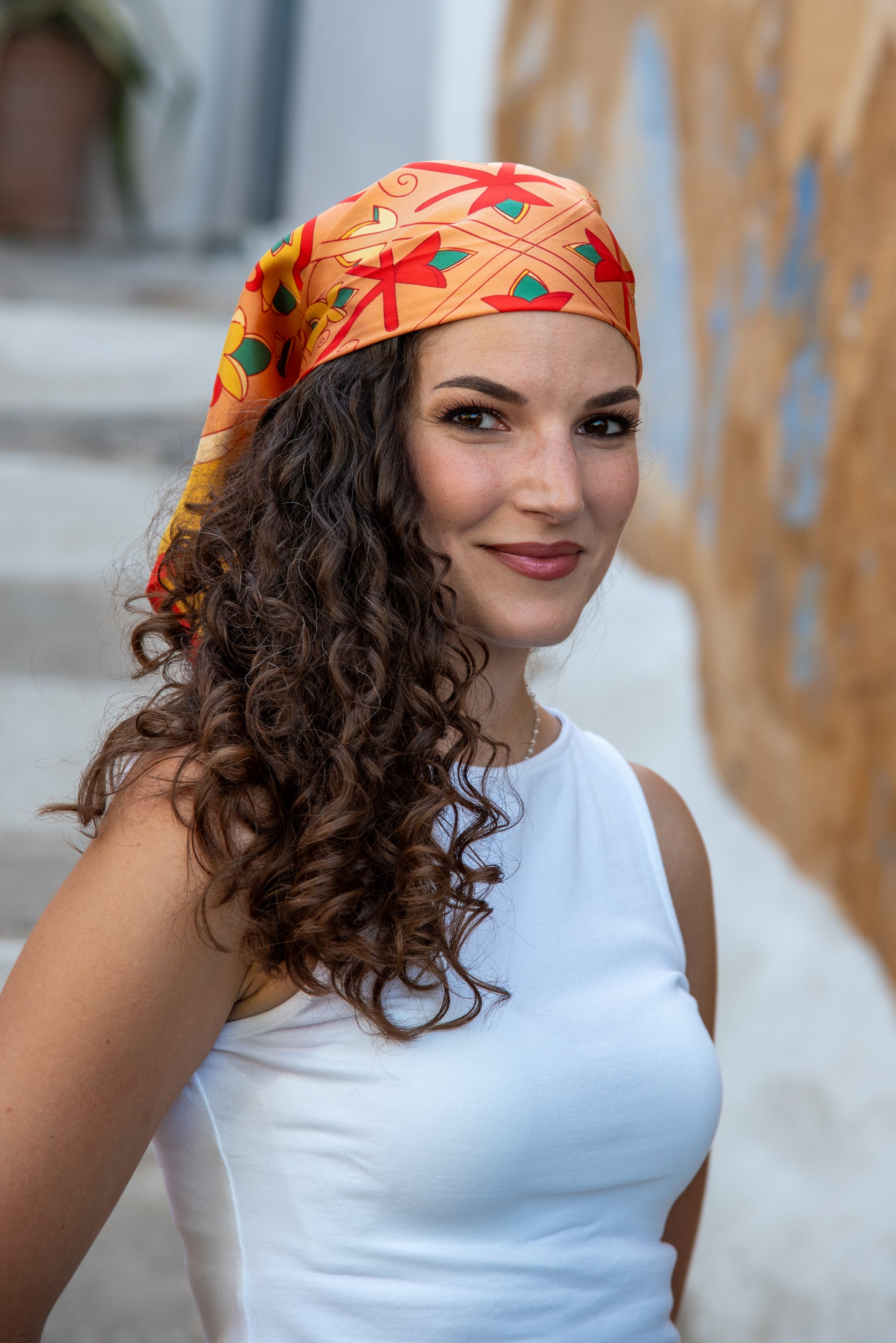 Model wearing Orange and Red Mesogeia Blooms silk scarf by Ariadne Kritonos tied as bandana