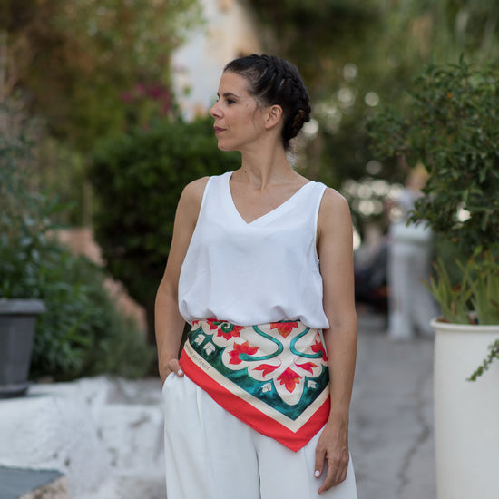 Woman styling the teal Attica Garden silk scarf on her waist, with pink Attica Garden scarf shown at end on second woman