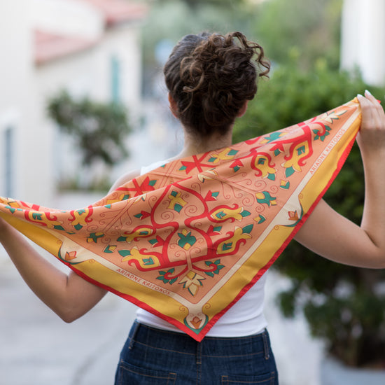 Model demonstrating Orange Mesogeia Blooms floral silk scarf in multiple styling options, ending with cream Mesogeia Blooms scarf shown on another model