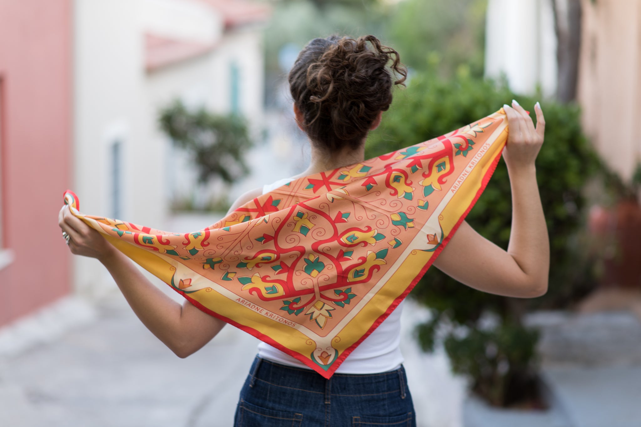 Model demonstrating Orange Mesogeia Blooms floral silk scarf in multiple styling options, ending with cream Mesogeia Blooms scarf shown on another model